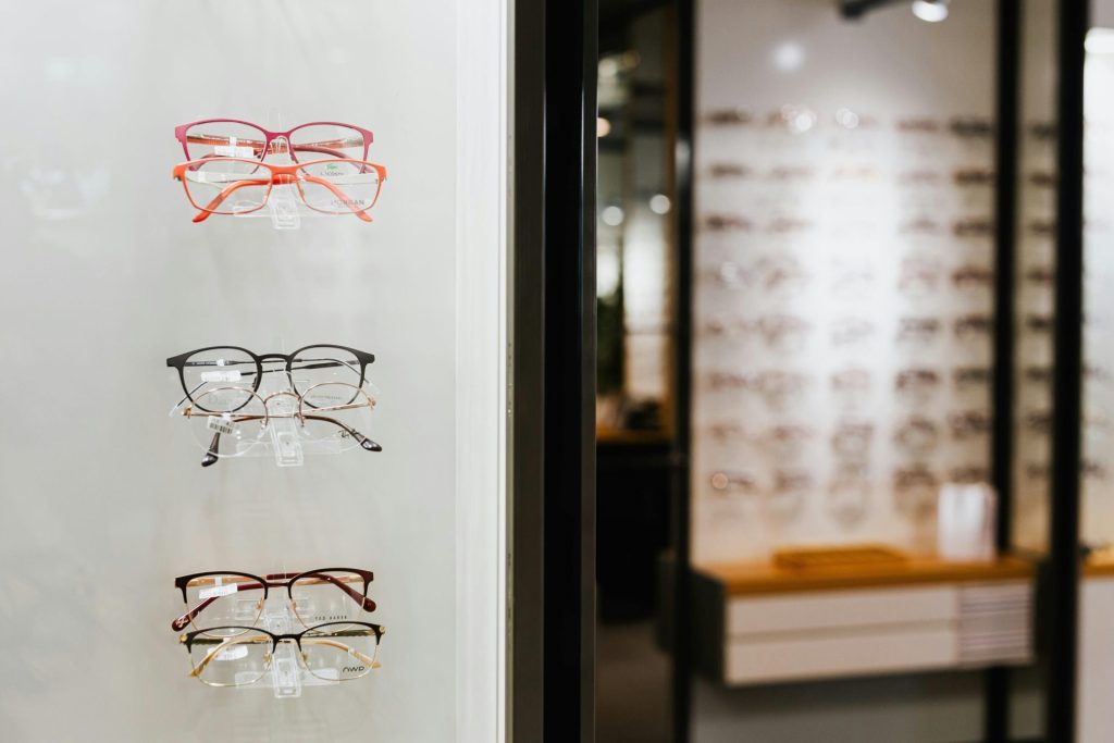 Divers modèles de lunettes sont présentés sur un présentoir mural dans un magasin d'optique.