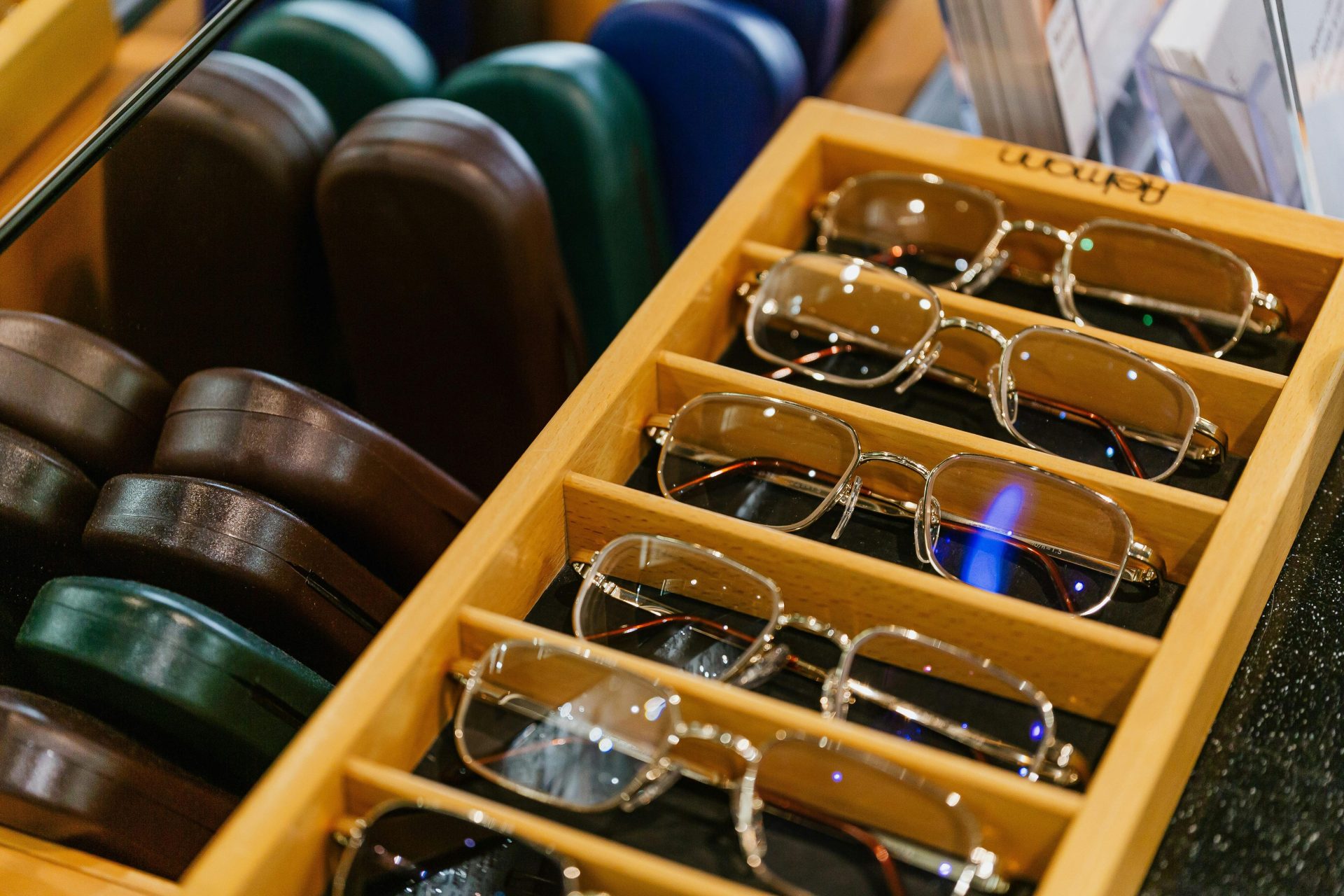Des lunettes soigneusement rangées dans une élégante vitrine en bois, chez un opticien.