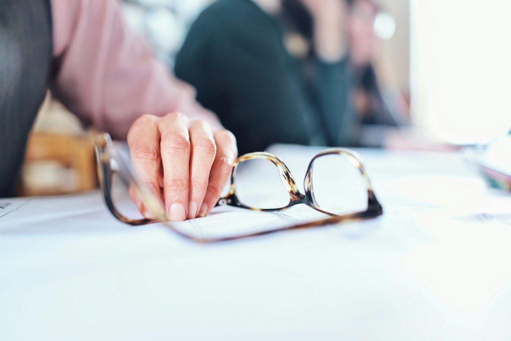 Un opticien aide une personne âgée à choisir ses lunettes.
